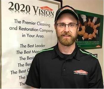 Male SERVPRO technician in glasses and hat smiling at the camera.