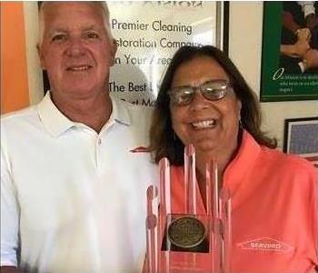 Man and woman smiling, holding award.