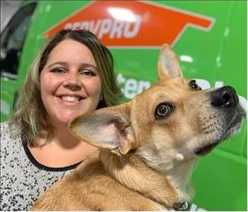 Woman standing in front of SERVPRO truck holding a dog.