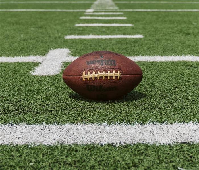 Football laying on its side on a football field.