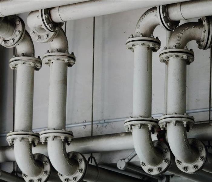 Four vertical white water pipes connecting to a larger system.